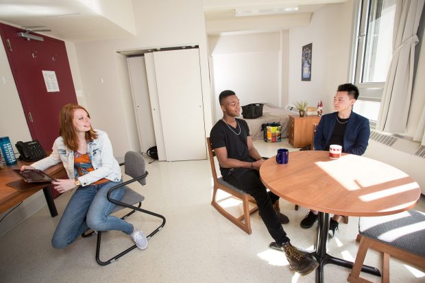 A group of three students studying and chatting at two tables in a bright, airy single room at Hingston Hall (HB)