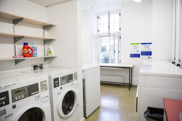 A clean, bright and airy laundry room at the Grey Nuns residence with several washing machines and tables for folding clothes.