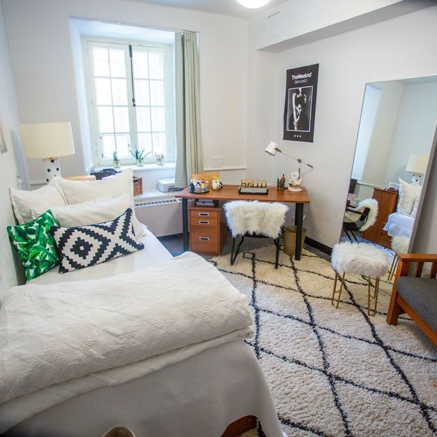 A cozy furnished bedroom in the Grey Nuns residence with a desk in the corner by a large window