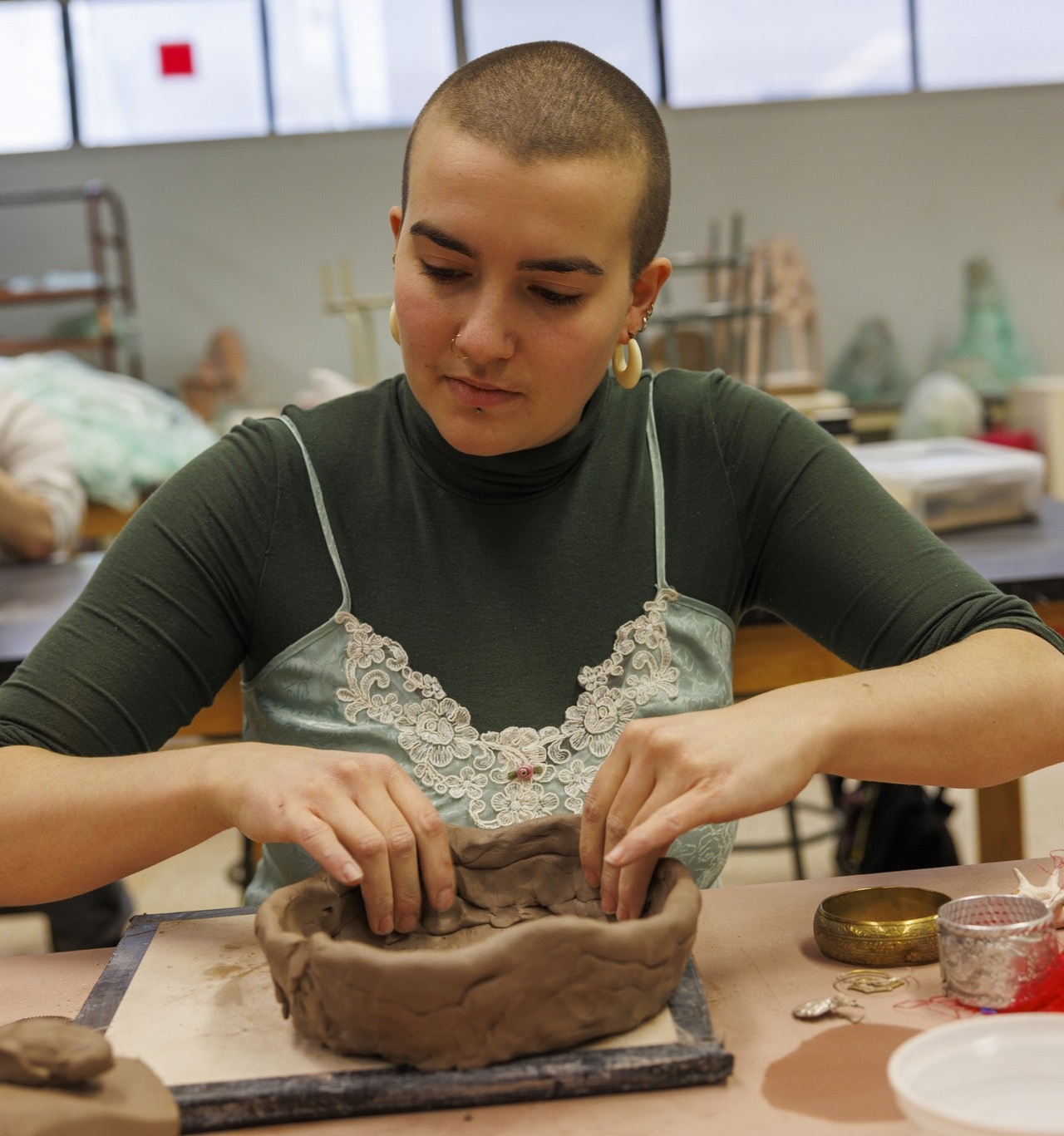 A woman in a studio works to create a clay bowl on a table. A woman in a studio works to create a clay bowl on a table.