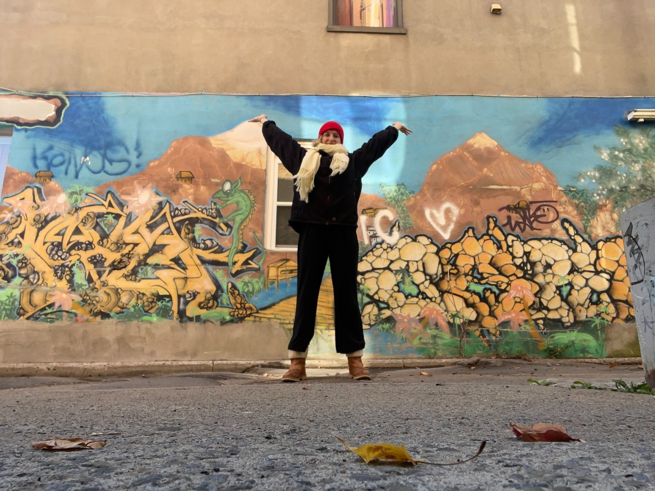 Amidst a November cold day, Jules mentor stands in front of Montreal street art with winter gear and her hands up. Amidst a November cold day, Jules mentor stands in front of Montreal street art with winter gear and her hands up.