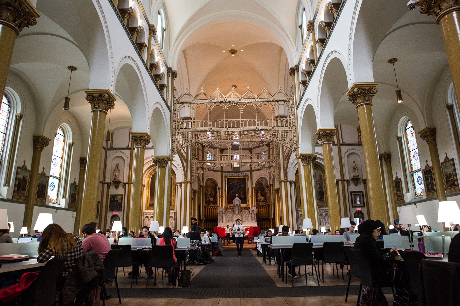 Students study in a beautiful chapel space with vaulted ceilings, ornate decor and lots of natural light. 