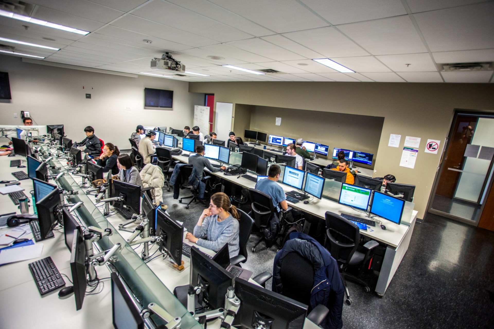 A lab filled with students and dual-monitor computers.