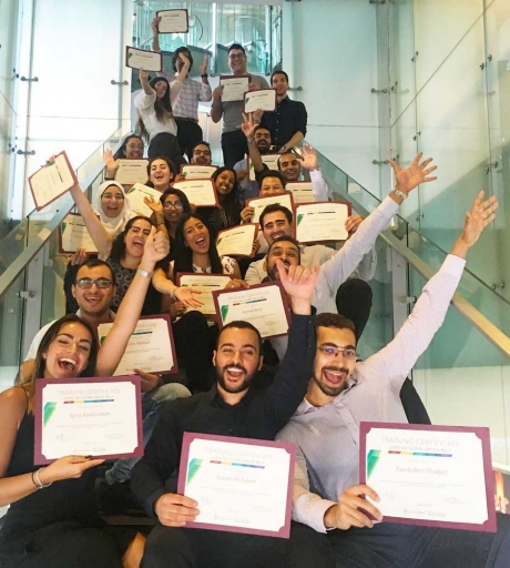 The first cohort of Lean Six Sigma group sitting on a set of stairs holding their certificates