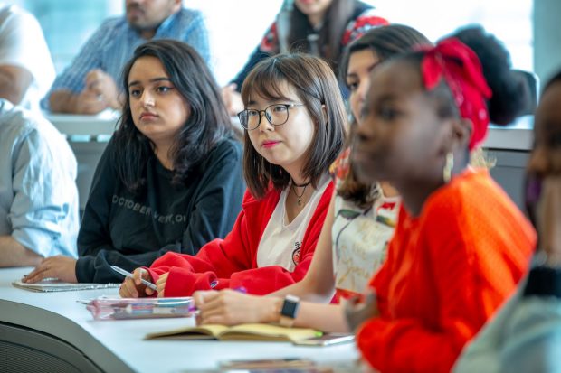 A group of attentive students sitting in a classroom, taking notes during a lecture.