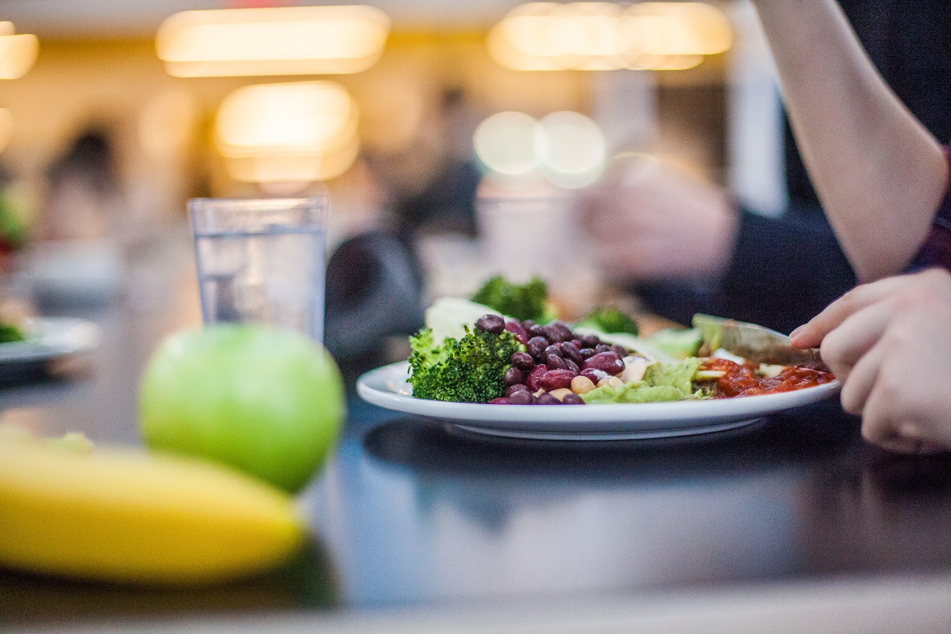 a table with fruit, water and a meal on a plate where a person is dining