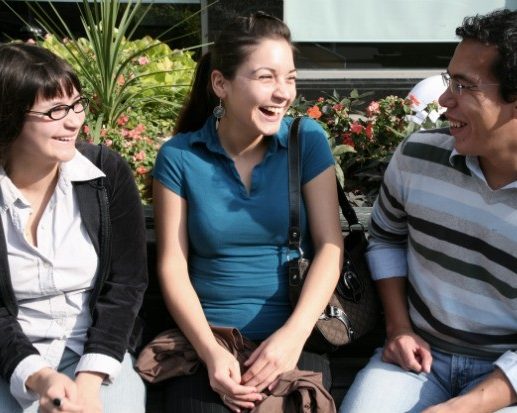 two women and a man seated and smiling in conversation