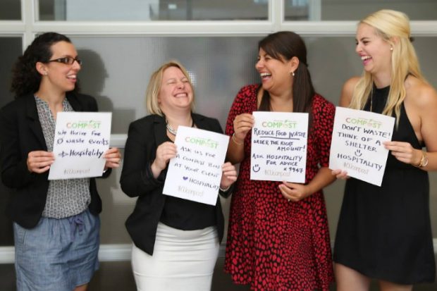 Four women laugh and hold up sheets where they have written their composting messages for Waste Not, Want Not.