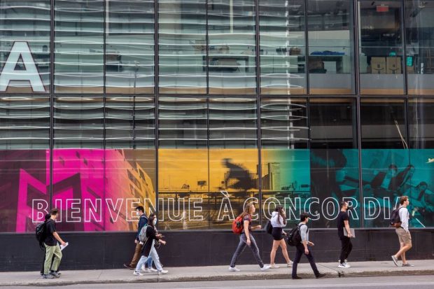 People walk past a building with colorful window displays and a sign that reads 
