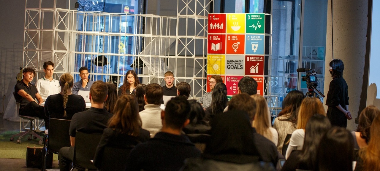 A crowd sitting in the 4th Space, listening to a presenter.