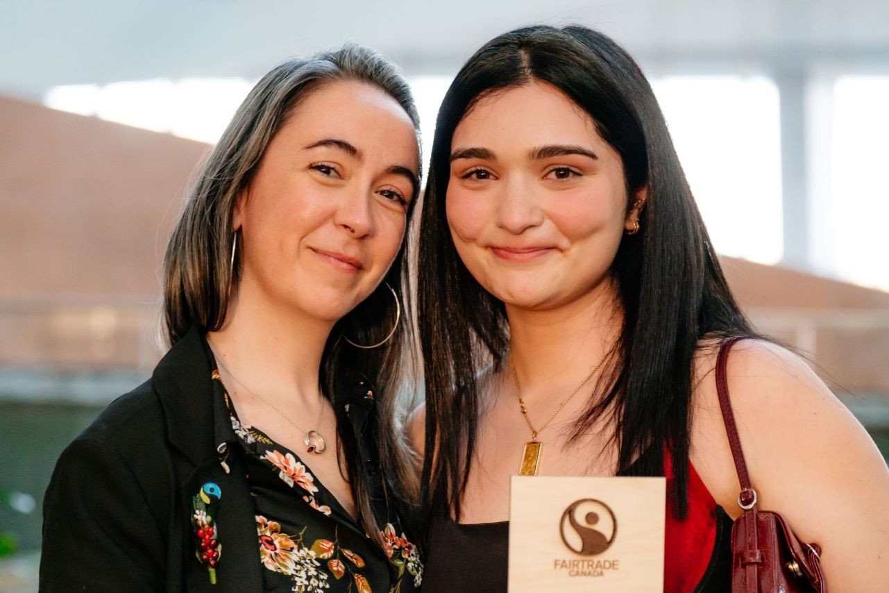 Two smiling women standing beside each other, one is holding an award