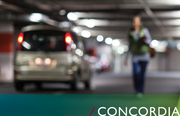 Image floue d'une personne marchant dans un parking faiblement éclairé, avec une voiture garée en arrière-plan et le texte « CONCORDIA » en bas.