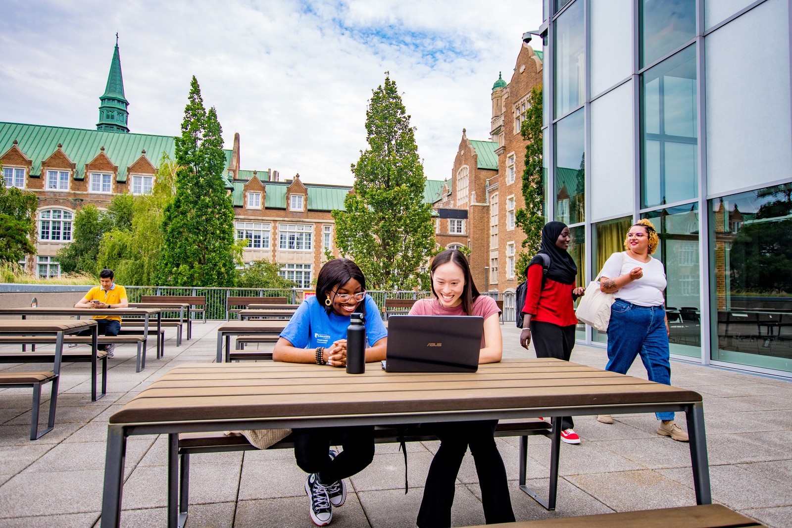 Concordia community members sitting on Loyola Campus terrace with a laptop