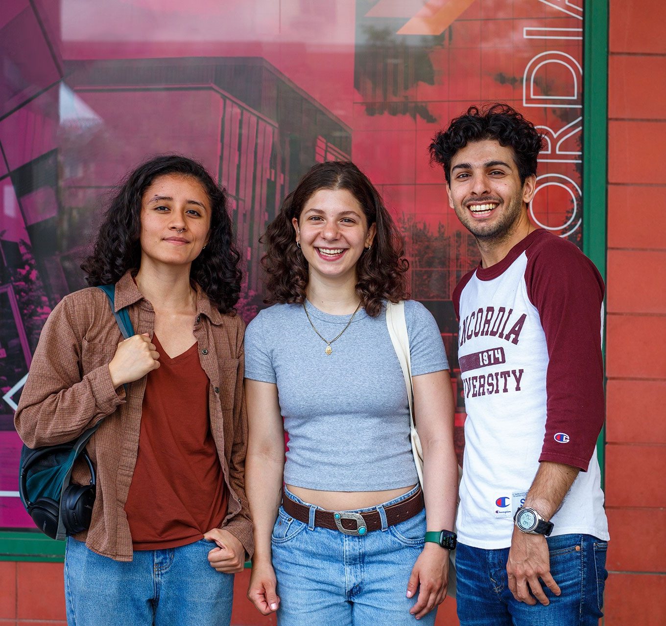 Trois étudiants, deux femmes et un homme à droite, regardent la caméra en se tenant debout et en souriant. Trois étudiants, deux femmes et un homme à droite, regardent la caméra en se tenant debout et en souriant.
