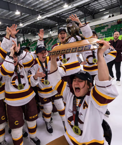 Une équipe de hockey féminin célèbre sa victoire en portant des médailles et en soulevant un trophée.