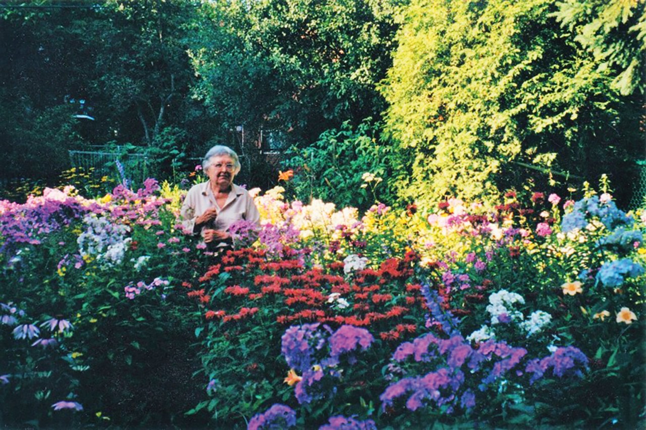 Laura Krasnodubsky se tient debout parmi ses fleurs s’élevant à hauteur de coude.