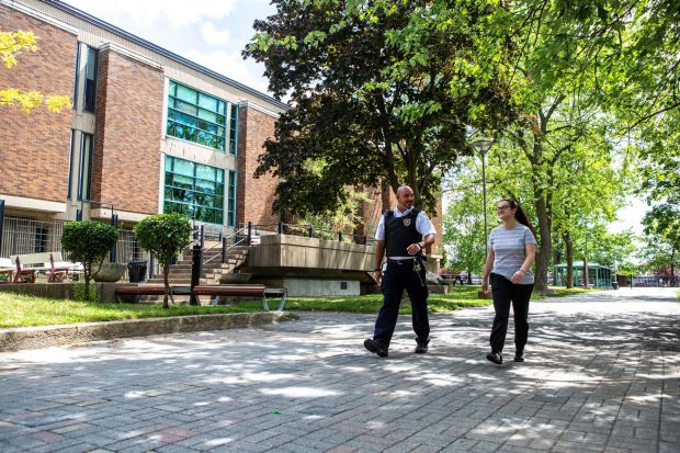 Un agent de sécurité se promène avec une femme sur le campus Loyola de Concordia