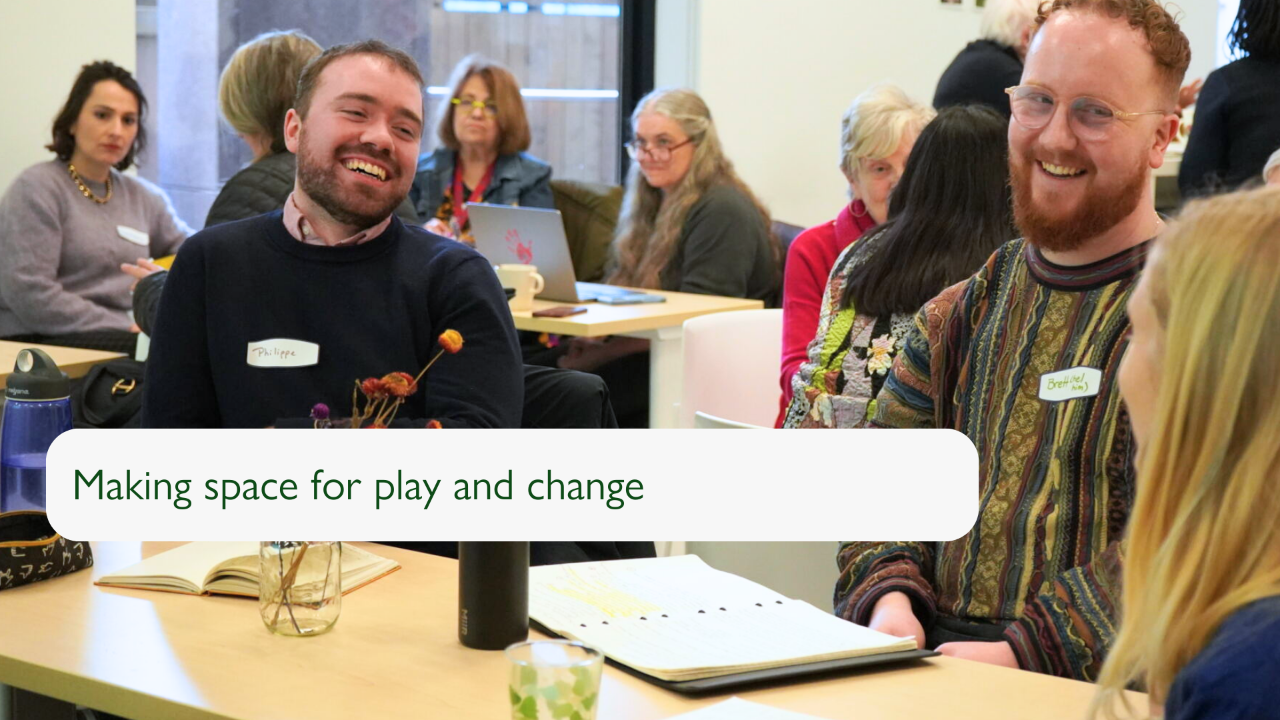 A slide with a photograph of three individuals sitting around a table laughing together, with two of the individuals facing the camera. The slide reads "Making space for play and change".