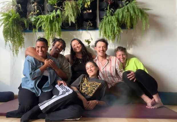 Critical mass of cyclists taking over a road. One of the bikes is pulling a car with seating, on which is a man playing an electric guitar.