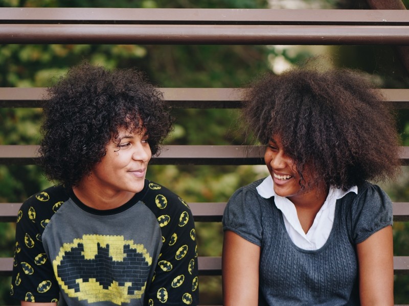 Deux adolescents noirs se regardent en souriant. 