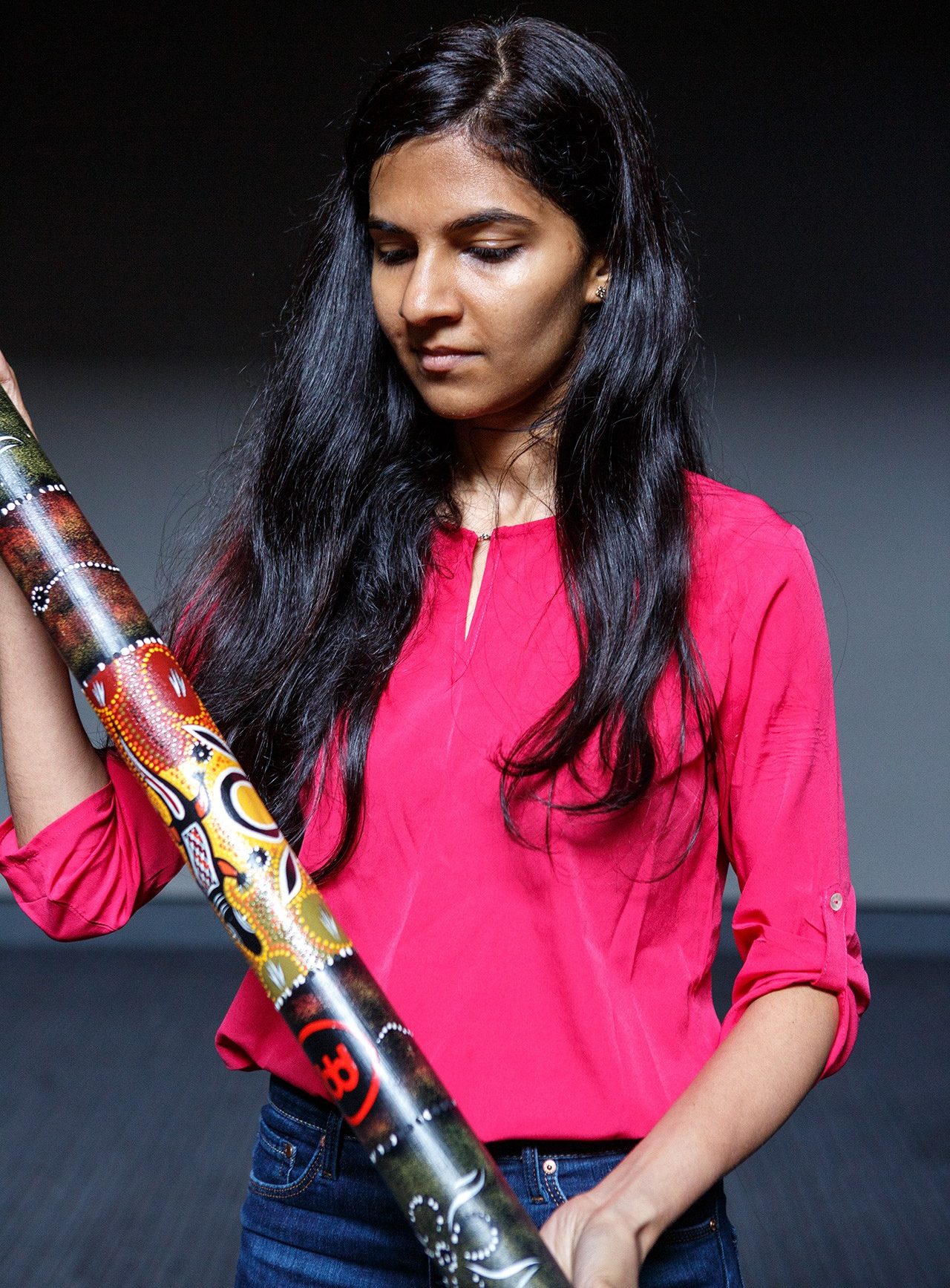 Female student holding a didgeridoo, an Australian indigenous instrument