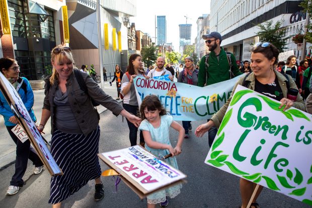people holding signs participate in a climate march walking past Concordia's downtown campus