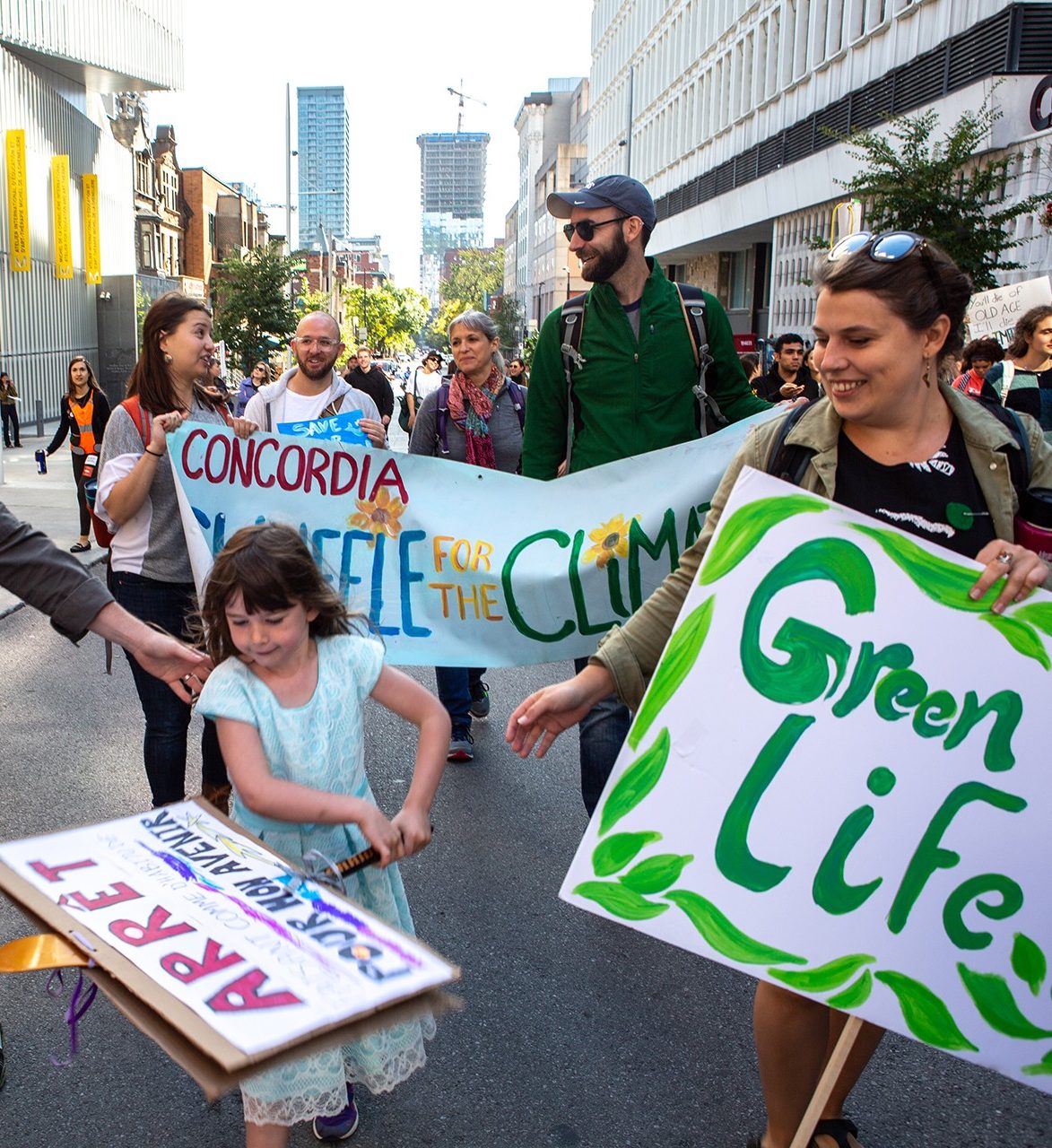 people holding signs participate in a climate march walking past Concordia's downtown campus