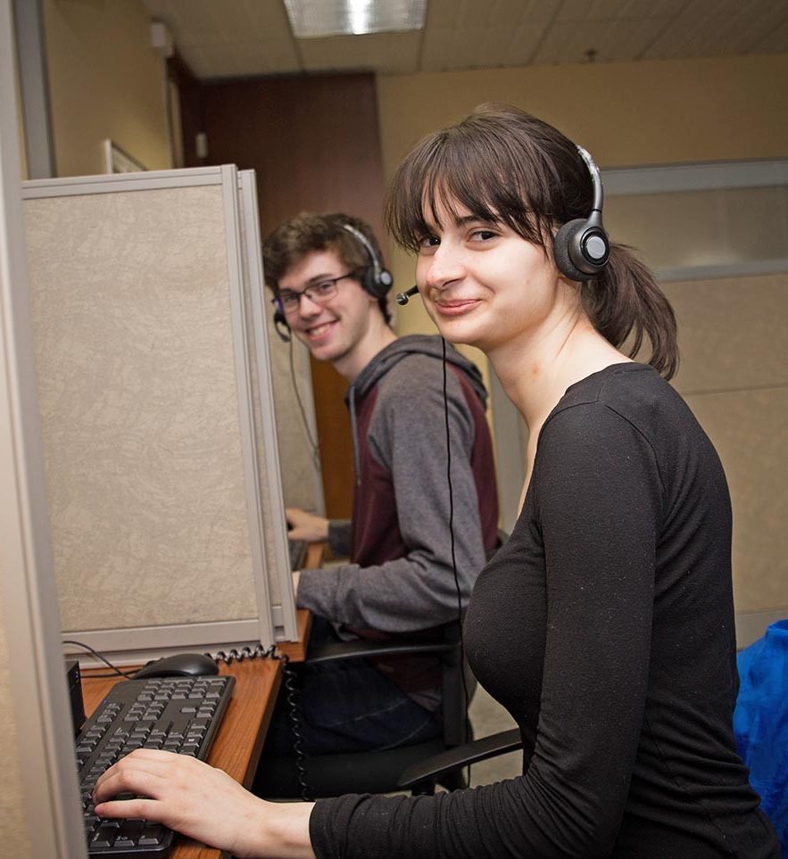 Une étudiante et un étudiant coiffés d’un casque d’écoute travaillent à l’ordinateur.