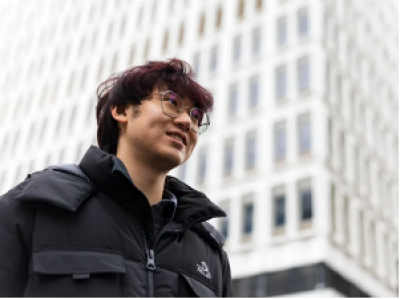  Un étudiant se tient devant un bâtiment blanc.