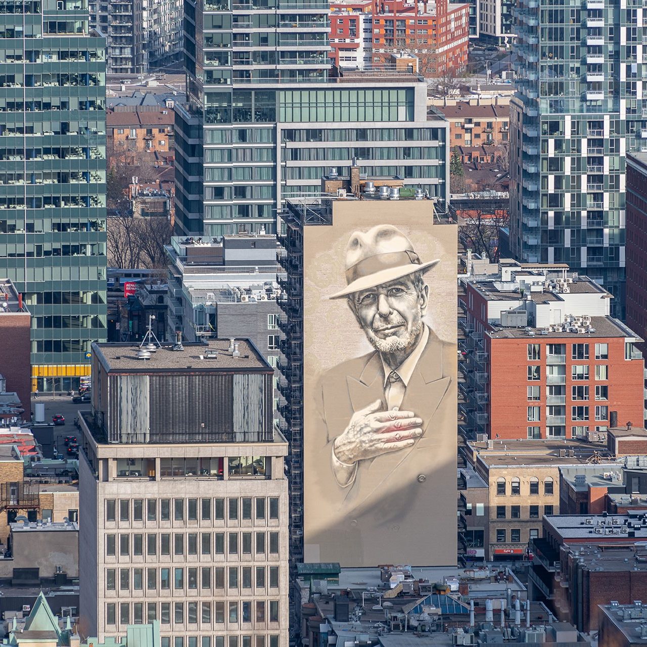 View of downtown Montreal showing a large mural of Leonard Cohen on one of the buildings.