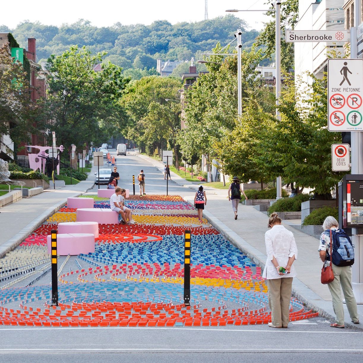 Various people admiring a colourful art display on the street.