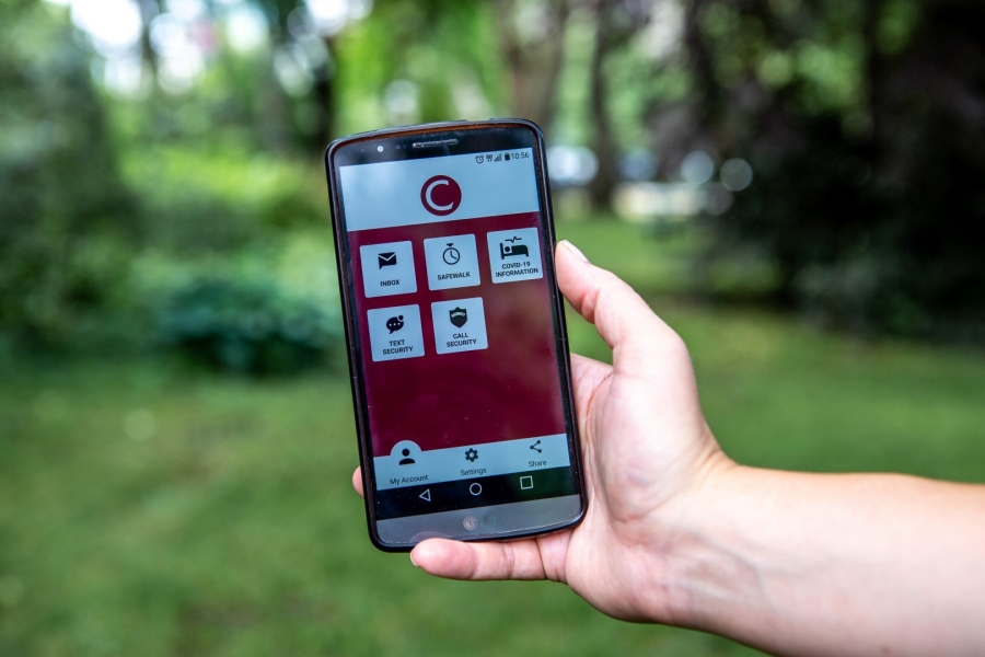 Un main tient un appareil numérique qui montre l'appli Rave Guardian