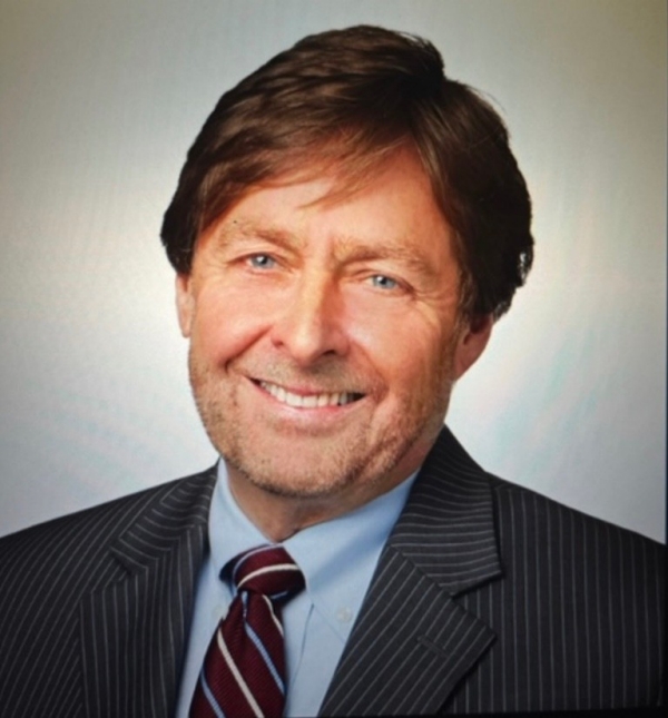 portrait of a man with brown hair, smiling, wearing a tie and dark jacket