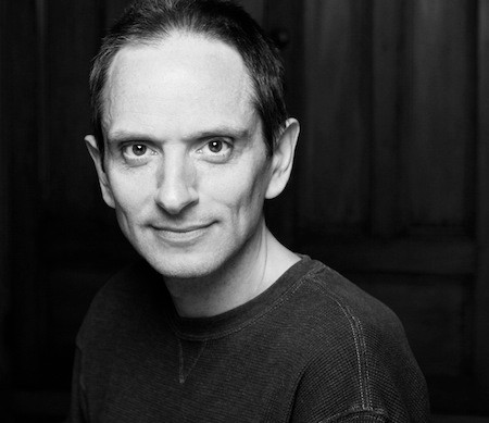 Black-and-white headshot of man with short dark hair