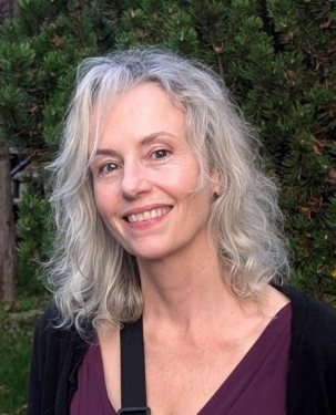 An image of a smiling grey-haired woman against a dark green background