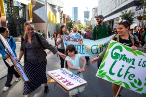 A photo of people outside on a sunny summer day holding signs in a protest demanding climate action