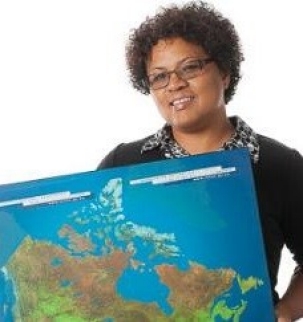 A woman in a black shirt holding a blue, green, and brown map of the world