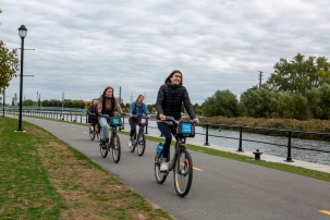Smiling people biking along a trail with water on one side
