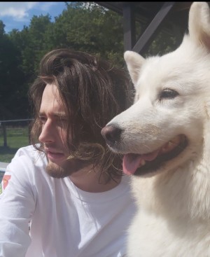 Zachary Lapointe sitting next to a white dog named Angea