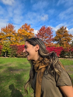 Bahareh Izadi laughing with a blue sky and autumnal trees in the background