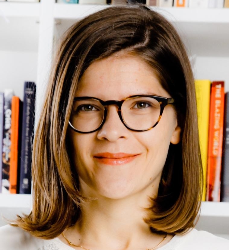 Headshot of portrait of woman with brown hair and brown glasses