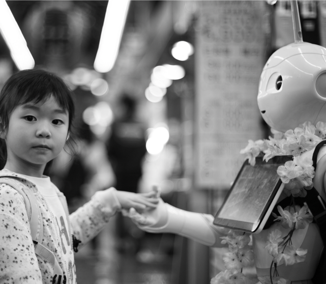 young girl placing her hand in robot's hand