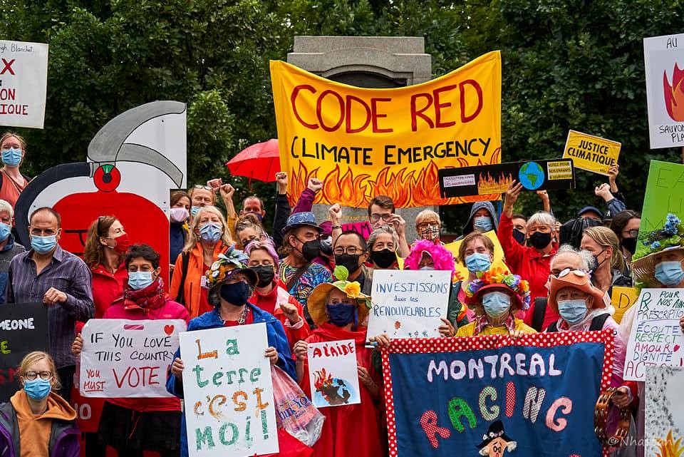 People holding protest signs outdoors during the Montreal Climate Justice protest