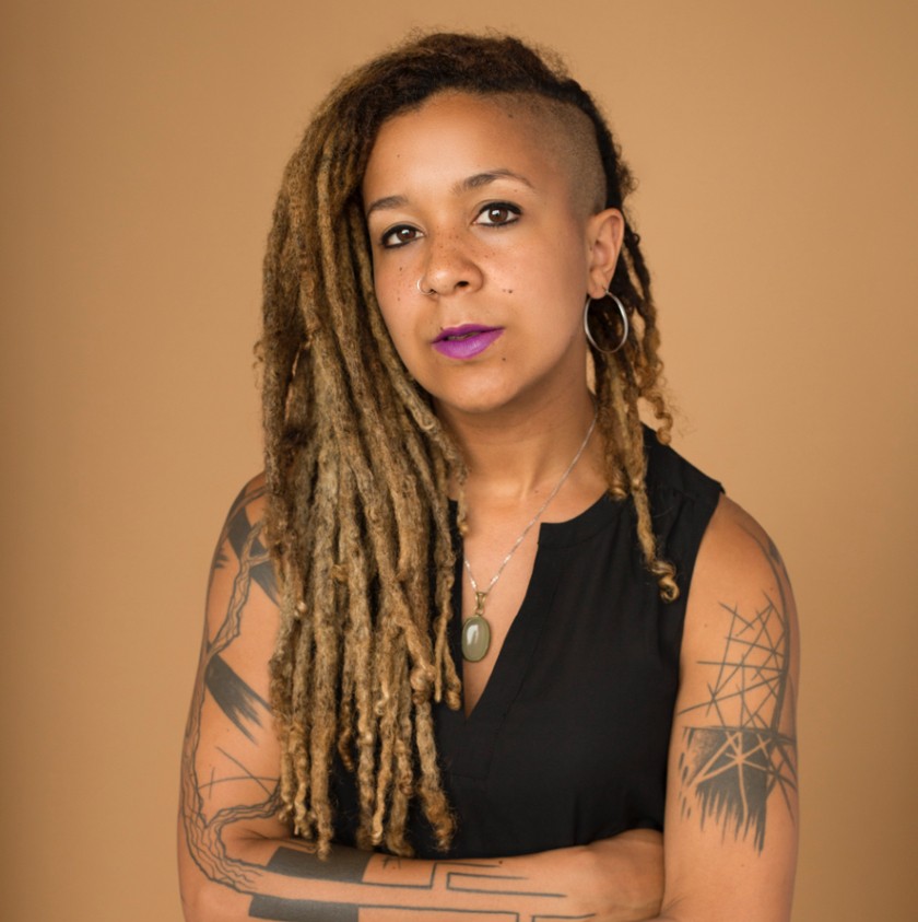 Portrait of woman with long hair and a few intricate black-and-white arm tattoos