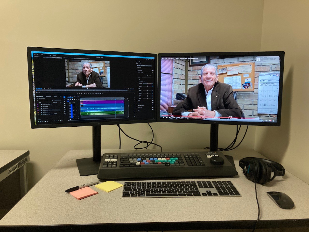Two computer monitors. One monitor displays video editing software, the other displays the image of an elderly man. 