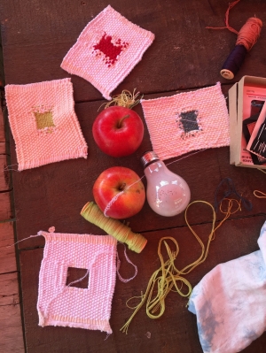 Artwork of crocheted squares arranged with a light bulb, apples, thread 