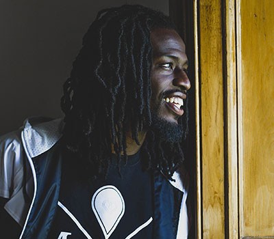 Smiling man learning against door frame