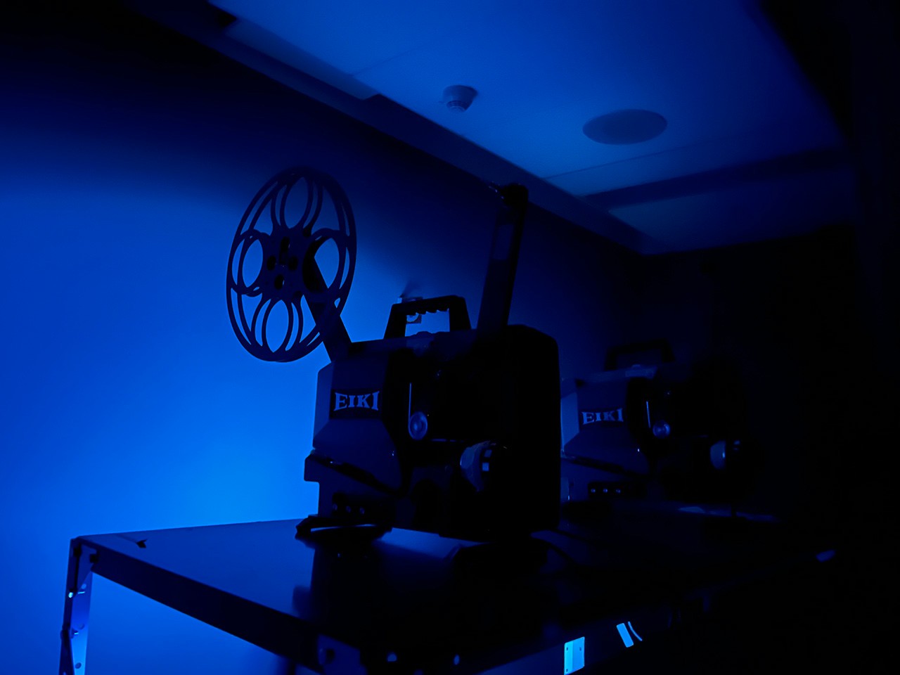 Projector in a room filled with blue light. 
