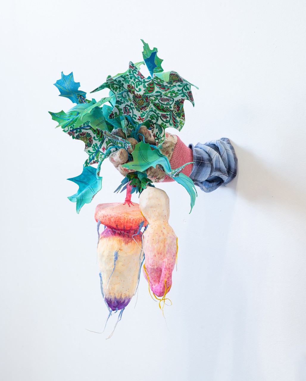 its a soft sculpture made of fabric. It's shaped like a hand holding out some root offerings, as if it was holding a bouquet of flowers
