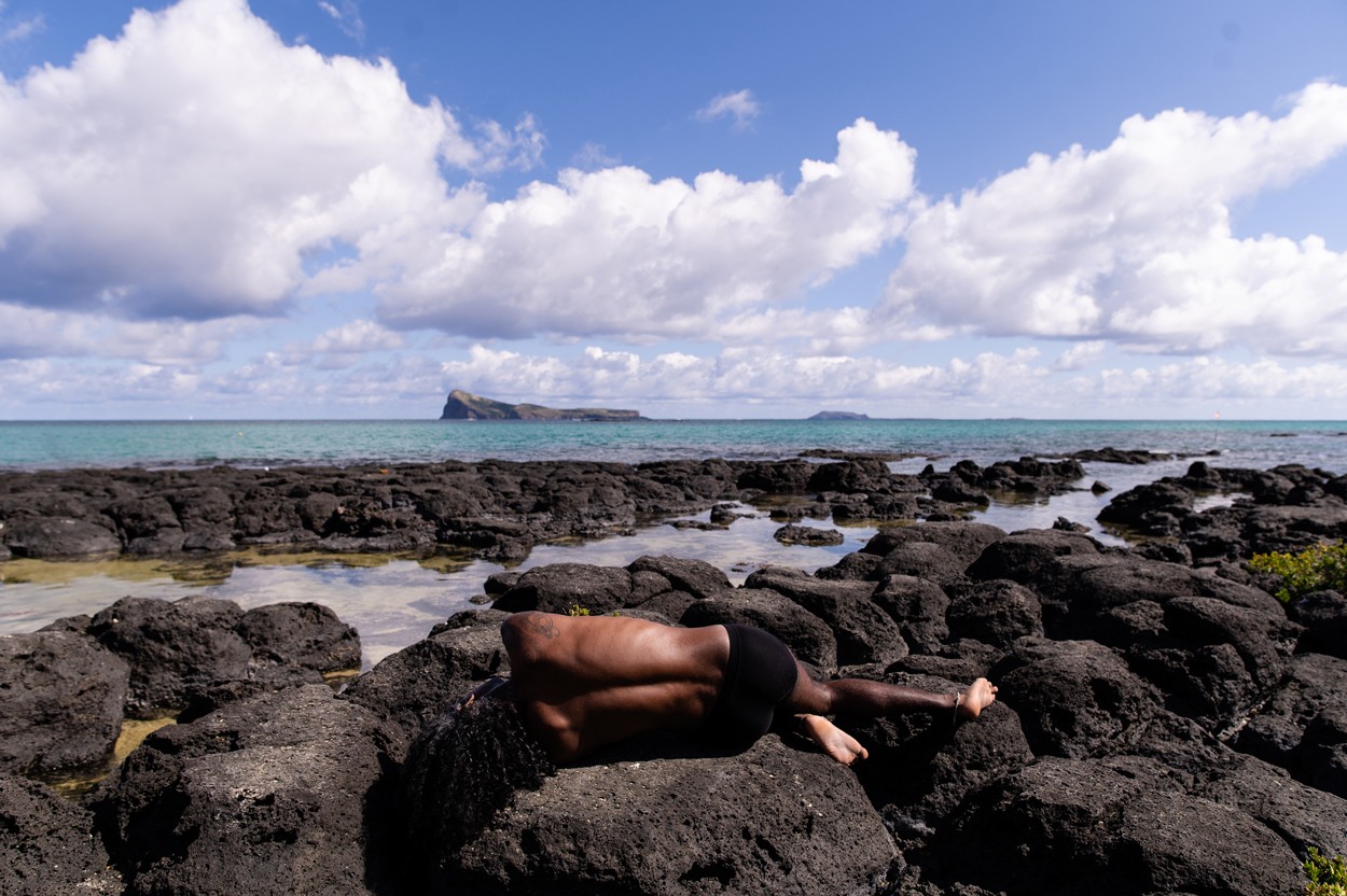 Kama's body is laying on a rocky seashore.